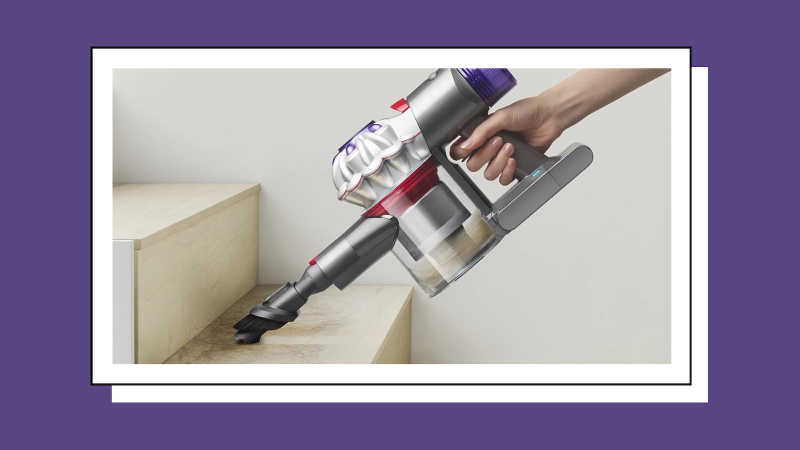 Handheld Dyson cordless vacuum using a brush attachment to clean hair from a light wood staircase, showcasing its lightweight design and powerful suction.