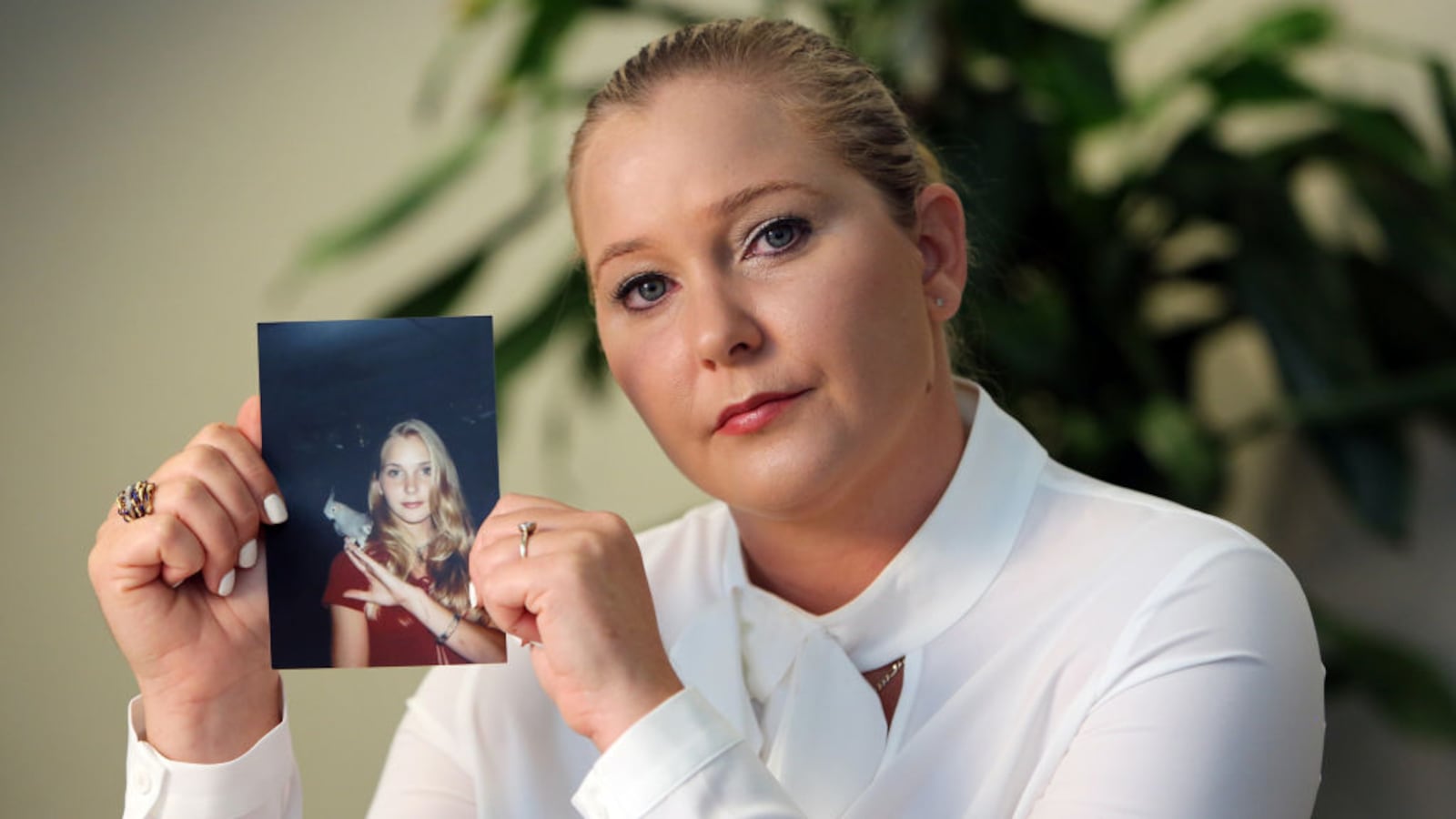 Epstein accuser Virginia Giuffre holds up a picture of herself as a young girl.