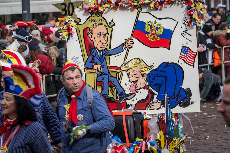 MAINZ, GERMANY - FEBRUARY 16: Carnival goer pull a poster showing US President Donald Trump licking Russian President Wladimir Putin's shoes during the annual Rose Monday parade on February 16, 2026 in Mainz, Germany. Rose Monday is the highlight of Carnival season, especially in western Germany, where parade float designers are famous for often searing and irreverent depictions of German and foreign politicians. (Photo by Thomas Lohnes/Getty Images)