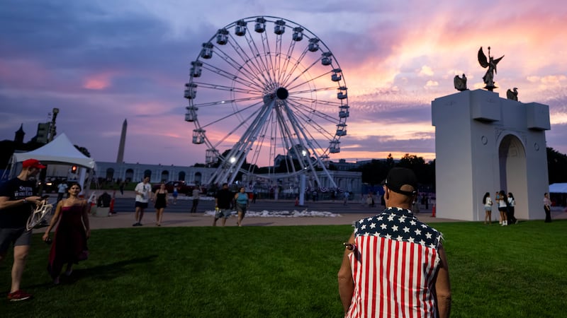 The sun sets behind a replica of the planned Triumphal Arch and the 110-foot "Freedom 250" ferris wheel on the first day of the Great American State Fair on the National Mall.
