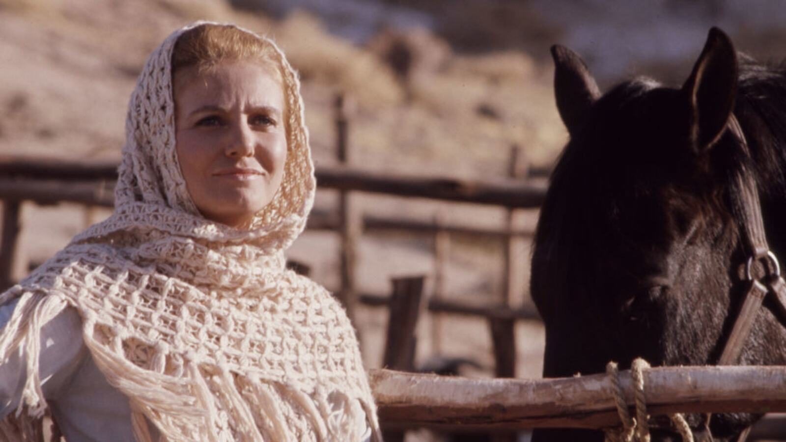 Sharon Acker standing outside next to a horse.