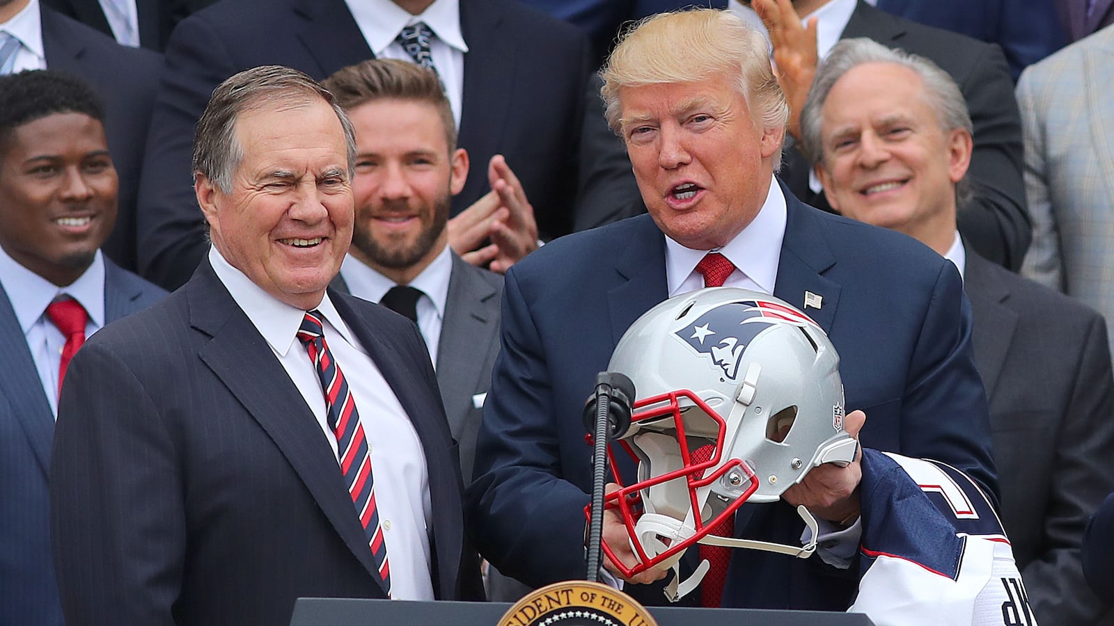 President Donald Trump holds a New England Patriots helmet while Patriots head coach Bill Belichick smiles.