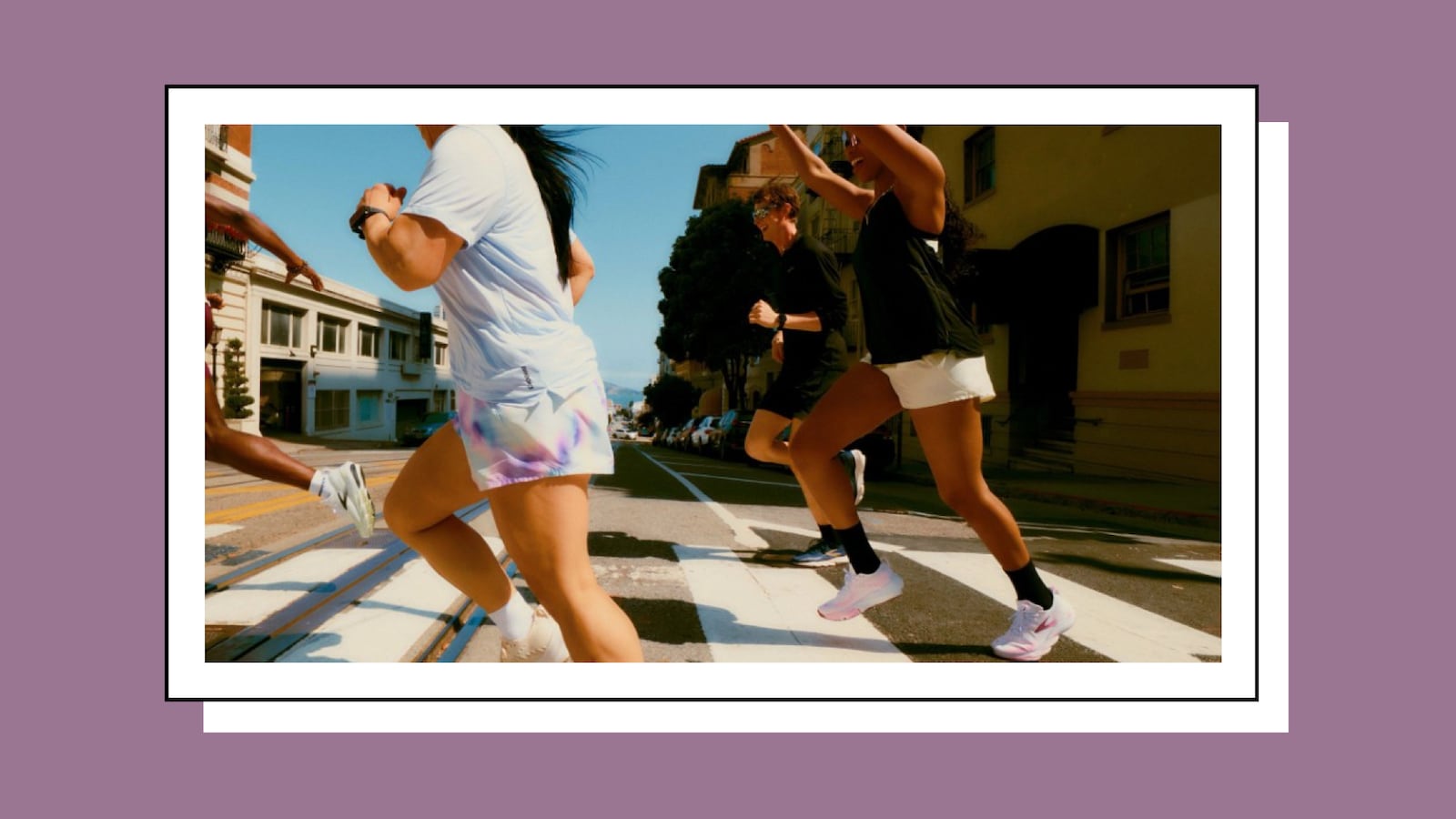 Group of runners crossing a San Francisco street in colorful athletic wear, including tie-dye shorts and black tops, framed like a Polaroid against a purple background.