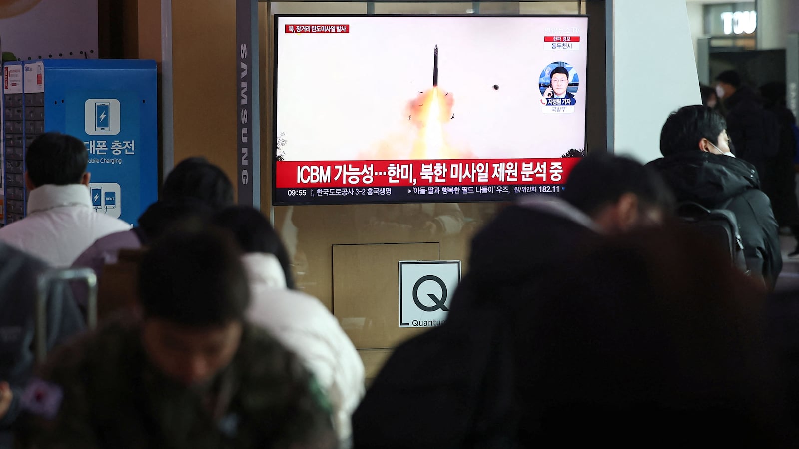 People watch a TV broadcasting a news report on North Korea firing what appeared to be a long-range ballistic missile