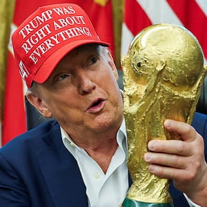 U.S. President Donald Trump wears a 'Trump Was Right About Everything!' hat while holding the FIFA World Cup Trophy, as he makes an announcement on the 2026 FIFA World Cup, in the Oval Office at the White House in Washington, D.C., U.S., August 22, 2025. REUTERS/Jonathan Ernst/File Photo