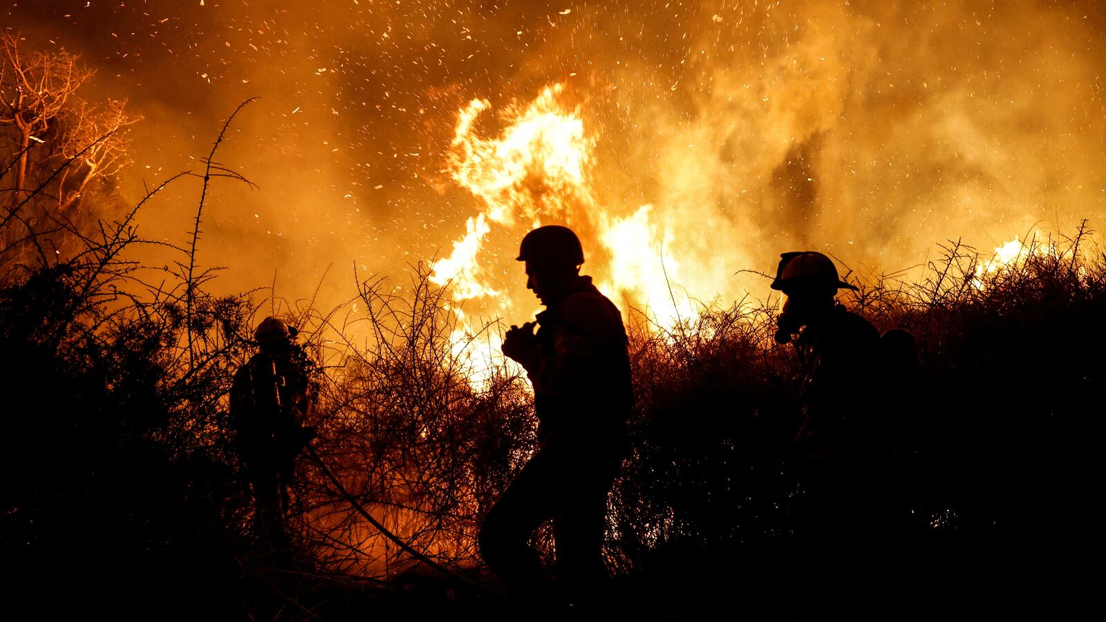 Firefighters work to put out a fire in an open field, following a mass-infiltration by Hamas gunmen from the Gaza Strip