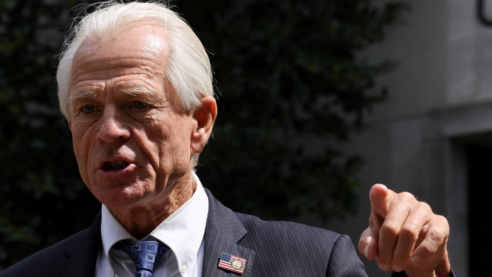 Peter Navarro, wearing a suit, speaks to reporters after a pre-trial conference in Washington.