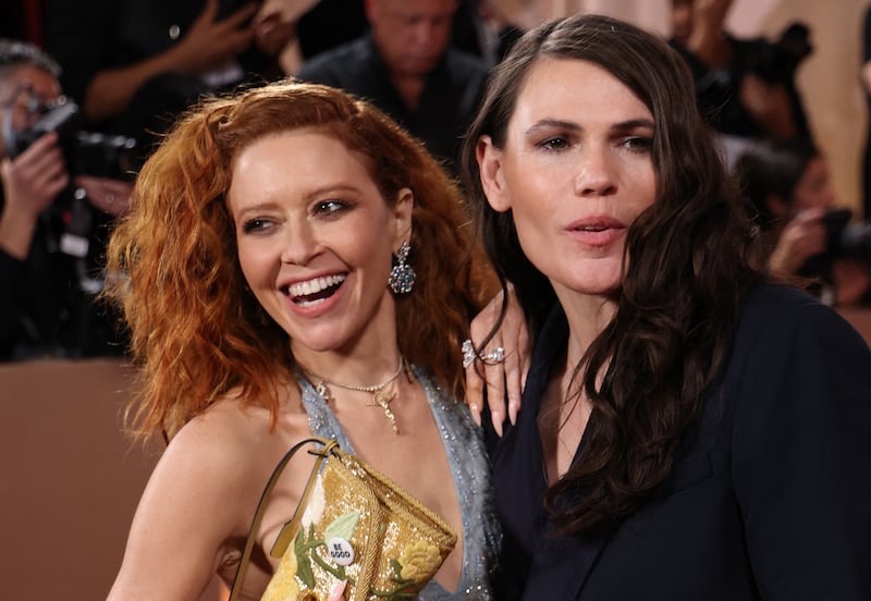 US actress Natasha Lyonne (L) holds up her purse with a pin reading "be Good", in tribute to Renee Good, who was fatally shot by a US Immigration and Customs Enforcement (ICE) agent in Minneapolis, as she and US actress Clea DuVall attend the 83rd annual Golden Globe Awards at the Beverly Hilton hotel in Beverly Hills, California, on January 11, 2026.