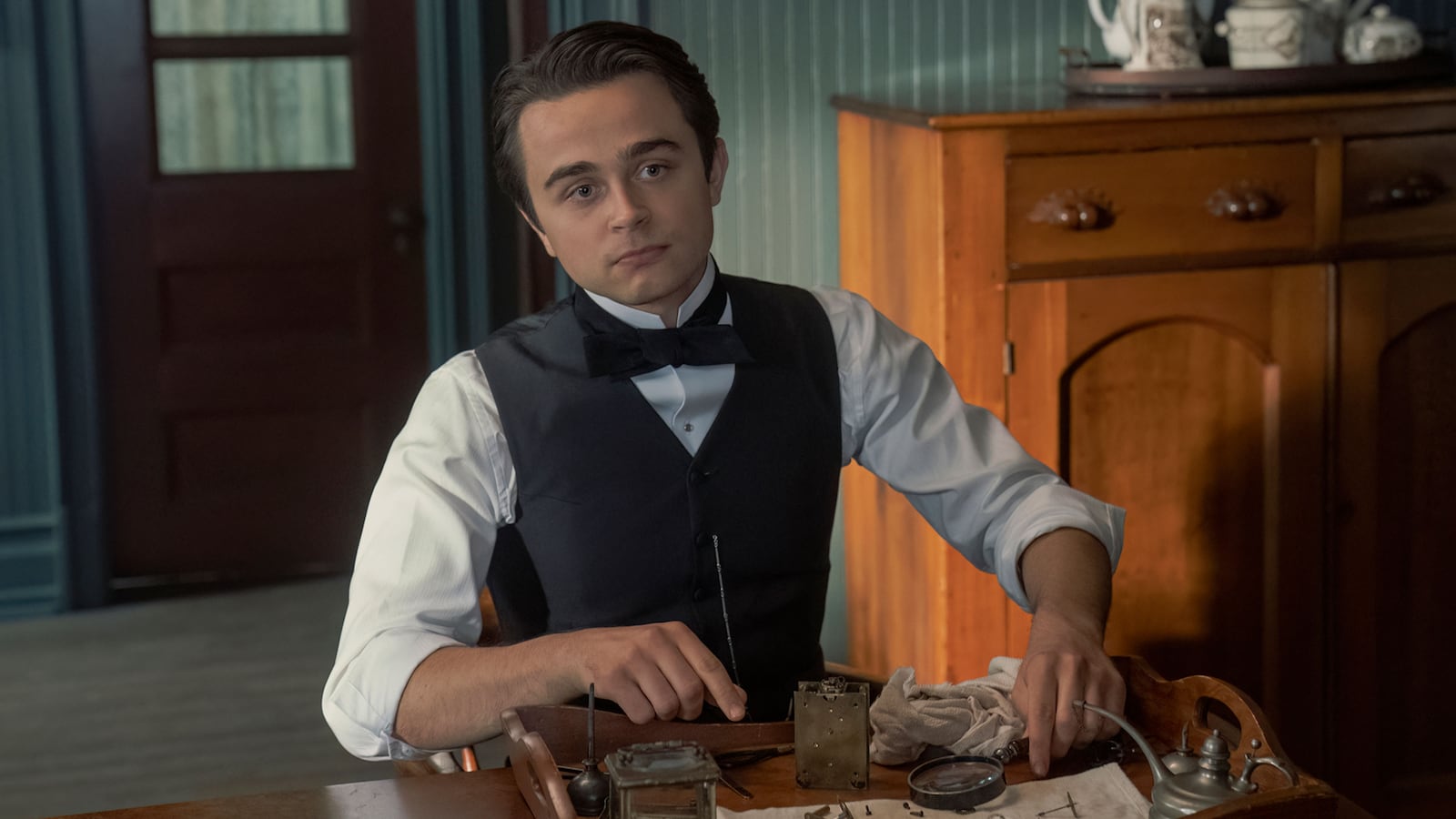 Ben Ahlers works on a clock at a table in 'The Gilded Age'