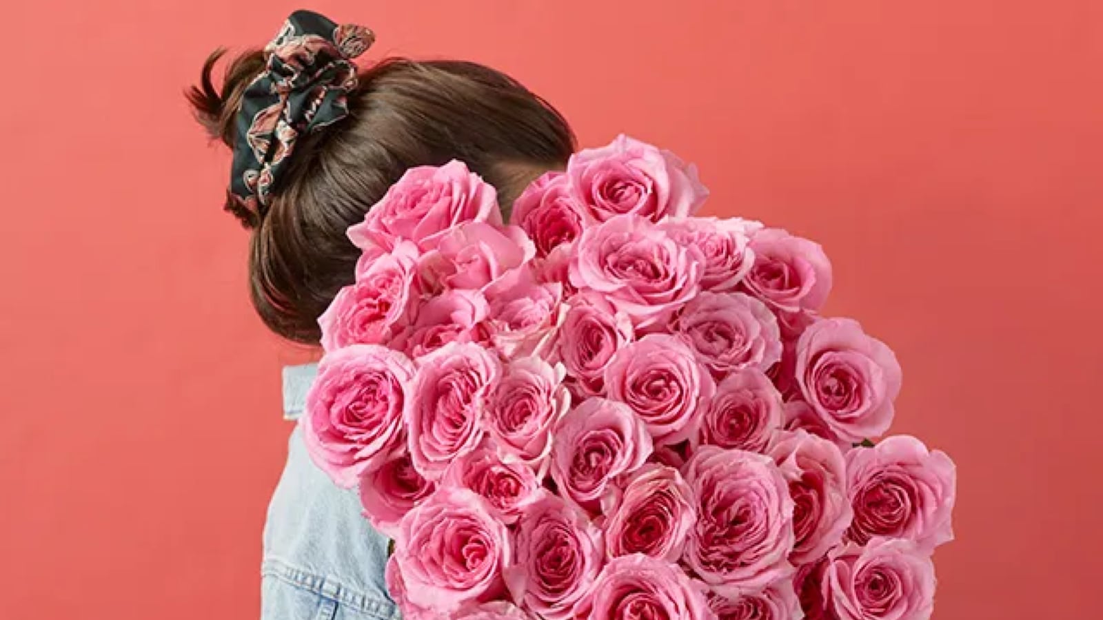 Farm-fresh pink rose bouquet from Bouqs held against a coral background, perfect for Valentine’s Day gifting