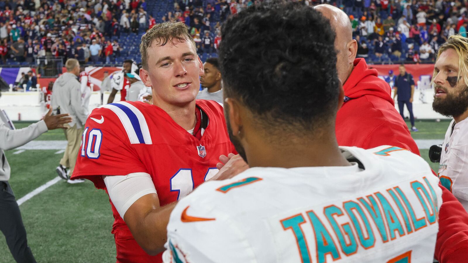 New England Patriots quarterback Mac Jones (10) talks to Miami Dolphins quarterback Tua Tagovailoa (1).