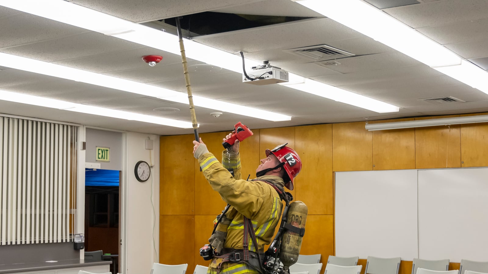 A member of the Fire Department checks the ceiling inside the District boardroom.