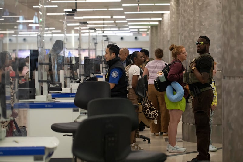 An Immigration and Customs Enforcement (ICE) agent stands behind a Transportation Security Administration officer as passengers travel through TSA screening after hundreds of Immigration and Customs Enforcement agents were ordered to deploy to airports to help fill TSA staffing gaps, at Hartsfield-Jackson Atlanta International Airport in Atlanta, Georgia, U.S., March 24, 2026. REUTERS/Alyssa Pointer