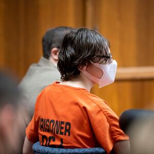 Ethan Crumbley, wearing a mask and an orange prison jumpsuit, stares forward in court.