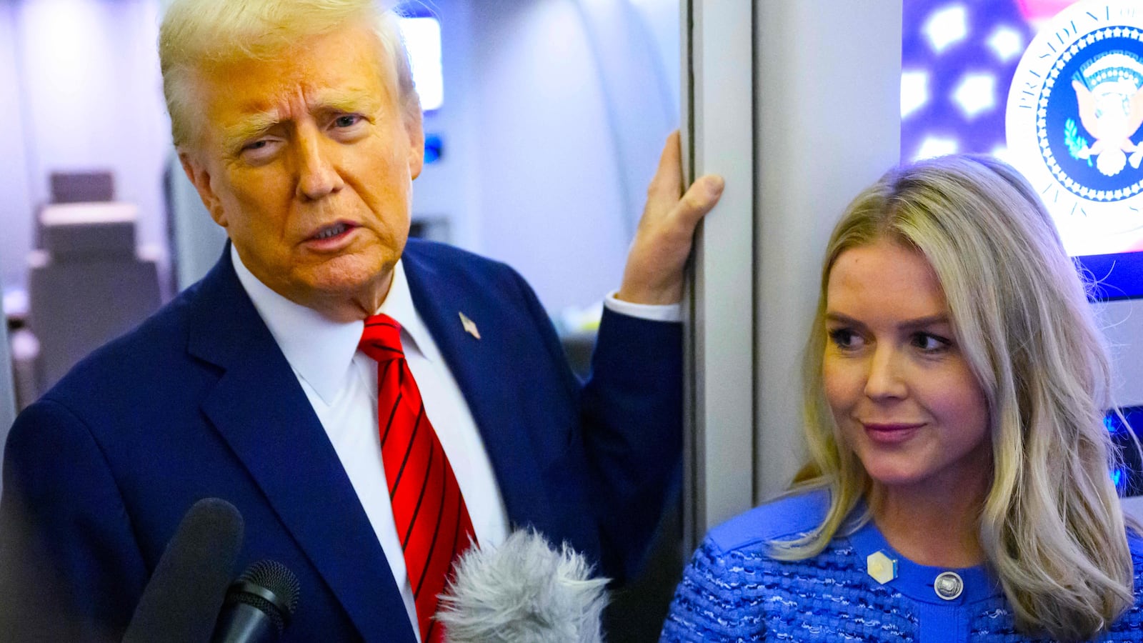 President Donald Trump, watched by White House Press Secretary Karoline Leavitt, speaks to reporters while in flight on Air Force One en route Joint Base Andrews, on January 27, 2025.