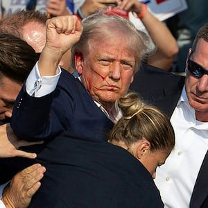TOPSHOT - Republican candidate Donald Trump is seen with blood on his face surrounded by secret service agents as he is taken off the stage at a campaign event at Butler Farm Show Inc. in Butler, Pennsylvania, July 13, 2024. Donald Trump was hit in the ear in an apparent assassination attempt by a gunman at a campaign rally on Saturday, in a chaotic and shocking incident that will fuel fears of instability ahead of the 2024 US presidential election.
The 78-year-old former president was rushed off stage with blood smeared across his face after the shooting in Butler, Pennsylvania, while the gunman and a bystander were killed and two spectators critically injured. (Photo by Rebecca DROKE / AFP) (Photo by REBECCA DROKE/AFP via Getty Images)