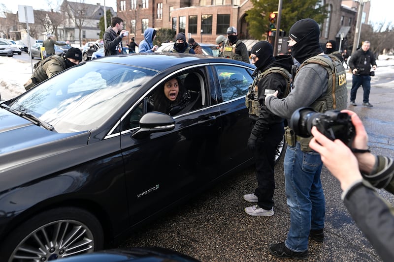 ICE agents confront a woman in a car before detaining her on January 13, 2026 in Minneapolis, Minnesota. The Trump administration has deployed over 2,400 Department of Homeland Security agents to the state of Minnesota in a push to apprehend undocumented immigrants.