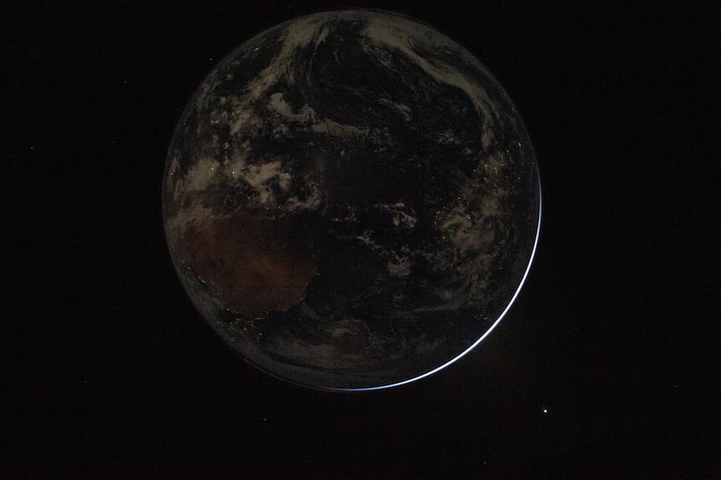 A view of a backlit Earth taken by NASA astronaut and Artemis II Commander Reid Wiseman from one of the Orion spacecraft's window after completing the translunar injection burn on April 2, 2026.
