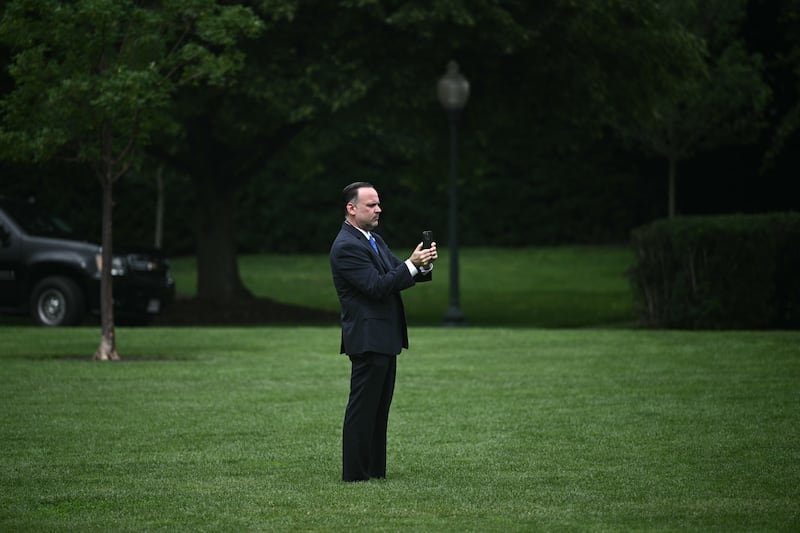 White House Deputy Chief of Staff Dan Scavino holds his phone as US President Donald Trump watches workers install a large flag pole on the South Lawn of the White House in Washington, DC on June 18, 2025. President Trump left the question of whether the United States will join Israeli strikes on Iran up in the air Wednesday, as he said that Tehran had reached out to seek negotiations. "I may do it, I may not do it. I mean, nobody knows what I'm going to do," Trump told reporters as he supervised the installation of a new flagpole on the White House South Lawn. (Photo by Brendan SMIALOWSKI / AFP) (Photo by BRENDAN SMIALOWSKI/AFP via Getty Images)