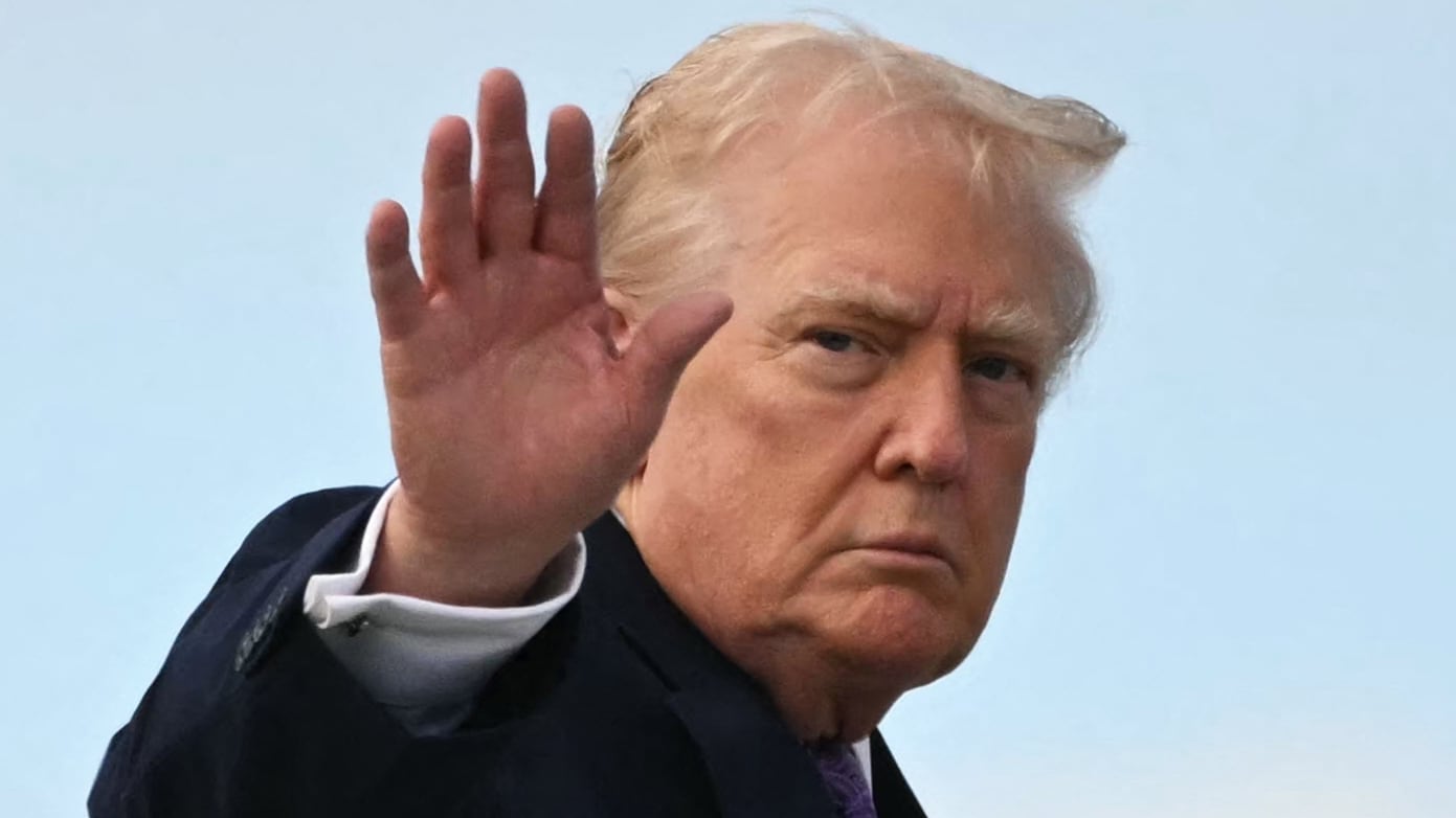 US President Donald Trump waves while boarding Air Force One at Palm Beach International Airport on November 30, 2025, on his way back to Washington, DC. President Trump and First Lady Melania Trump spent the Thanksgiving holiday at his Mar-a-Lago residence. (Photo by Jim WATSON / AFP via Getty Images)