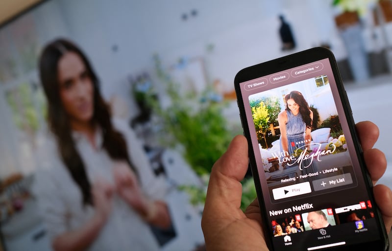 A person holds a smartphone displaying Netflix's new Meghan Markle show.