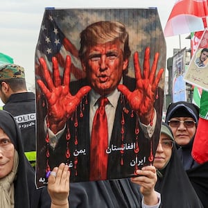 TOPSHOT - Women march with a sign depicting US President Donald Trump with bloodied hands in Tehran on February 11, 2026, during a rally marking the 47th anniversary of the 1979 Islamic revolution. The Persian calendar date of Bahman 22 celebrates the anniversary of the resignation of the ousted shah's last prime minister and the formal assumption of power by revolutionary leader Ayatollah Ruhollah Khomeini. (Photo by AFP via Getty Images)