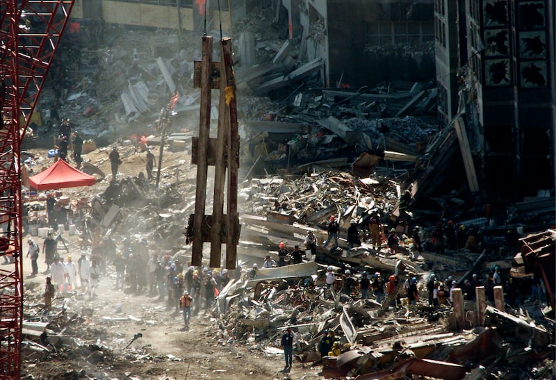 A large piece of the shell of World Trade Center Tower One is hoisted by a crane over the heads of rescue and recovery workers still passing wreckage of the collapsed complex out by hand in a bucket brigade, September 17, 2001.