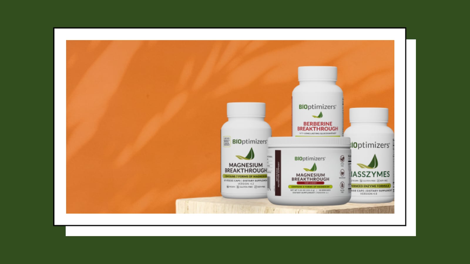 Lineup of BIOptimizers supplement products displayed on a wooden block against a warm orange background, including Magnesium Breakthrough (capsule bottle and powder tub in Tart Cherry), Berberine Breakthrough, and MassZymes.