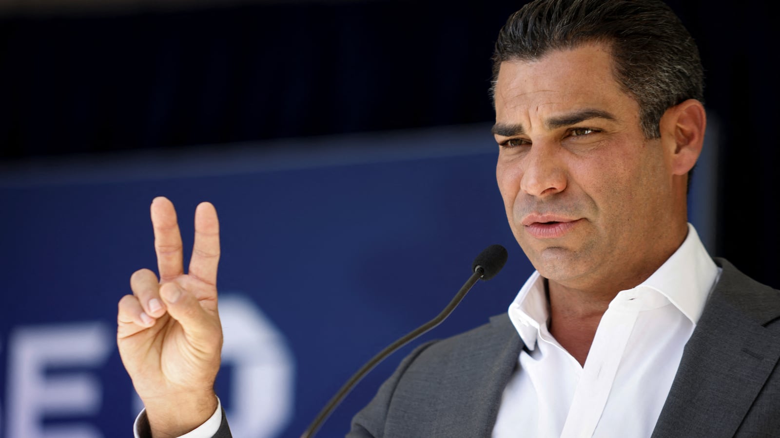 Mayor Francis Suarez flashes a peace sign as he speaks during an event on stage.