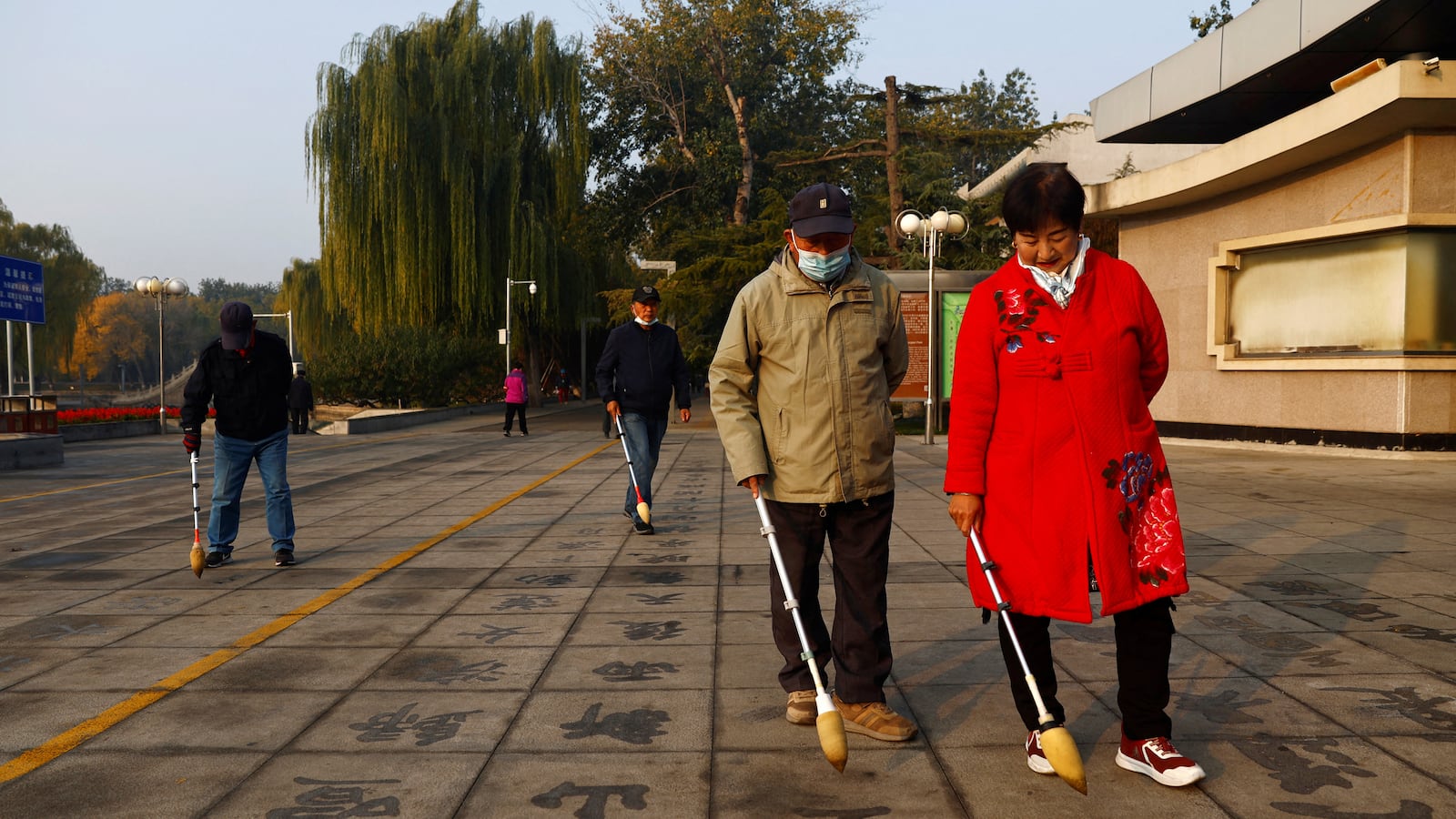 Elderly people practise Chinese calligraphy on the ground at a park in Beijing, China November 10, 2022.
