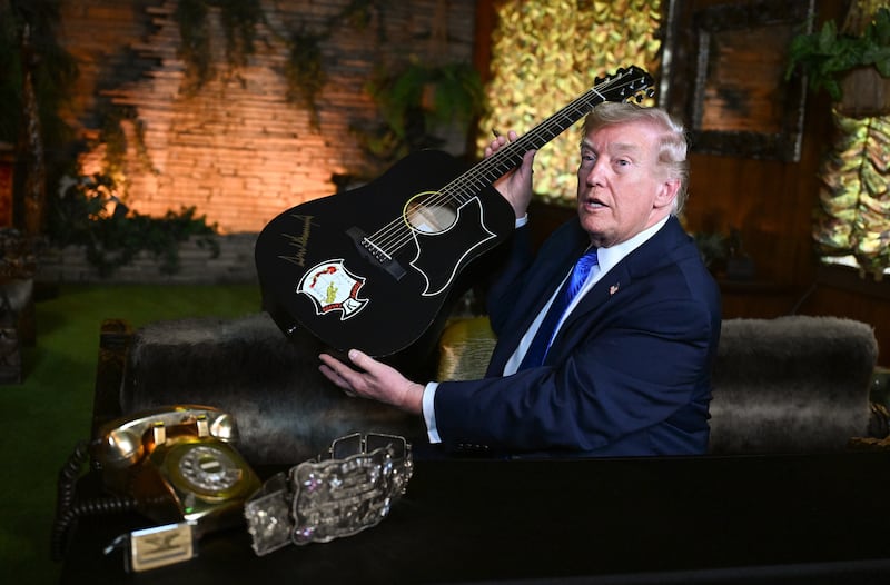 MEMPHIS, TENNESSEE - MARCH 23: U.S. President Donald Trump holds up a replica of an Elvis Presley guitar after signing it while visiting Graceland, the Presley's home, on March 23, 2026 in Memphis, Tennessee. President Trump visited Graceland after participating in a Memphis Safe Task Force roundtable on combating violent crime. (Photo by Roberto Schmidt/Getty Images)