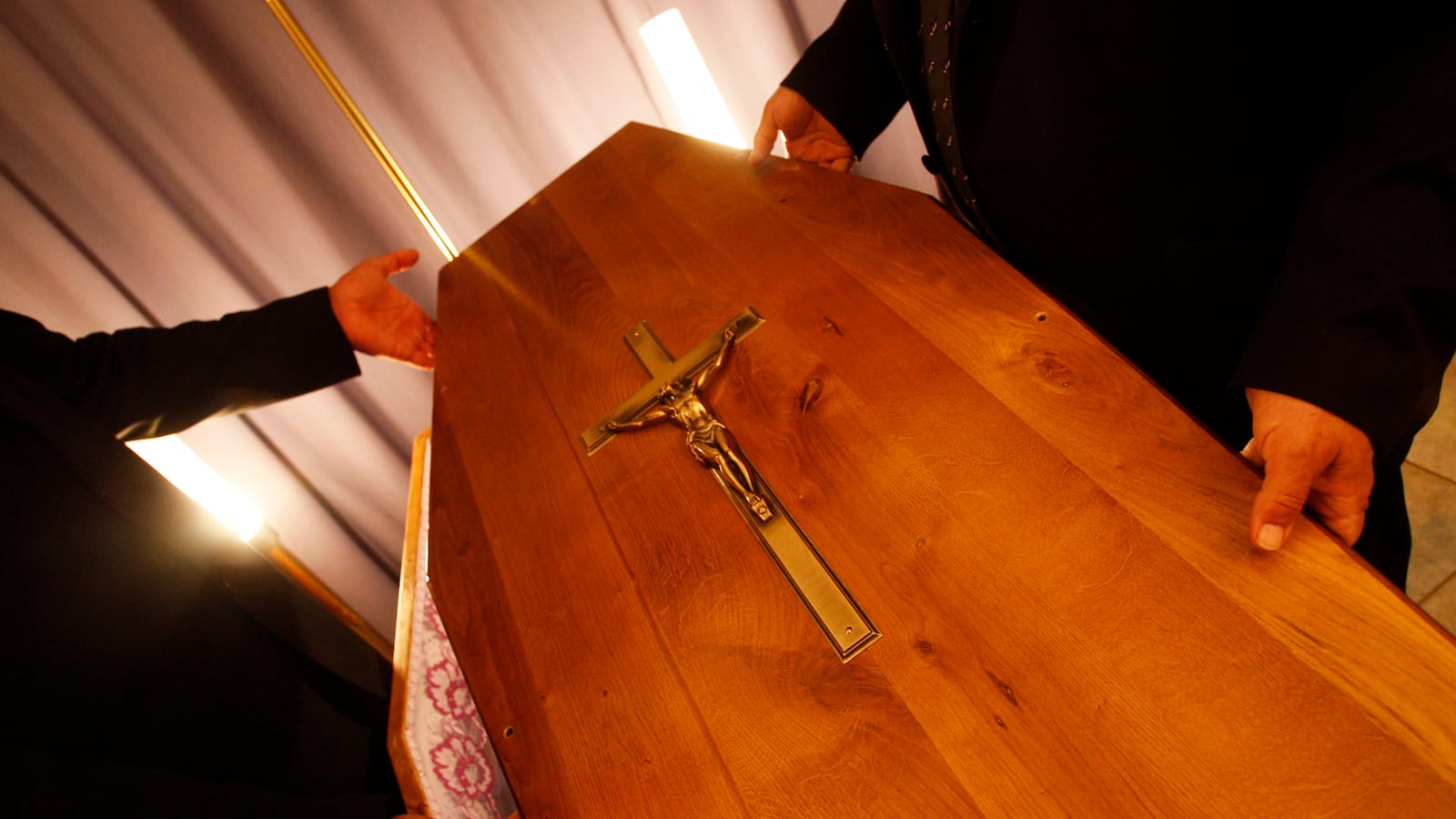 Regional funeral parlour employees place the lid on a coffin as they finish funeral preparations in Pessac, southwestern France.