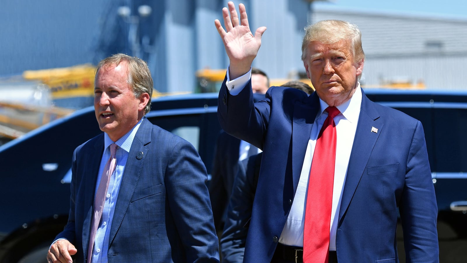 President Donald Trump waves upon arrival, alongside Attorney General of Texas Ken Paxton (L) in Dallas, Texas, on June 11, 2020.