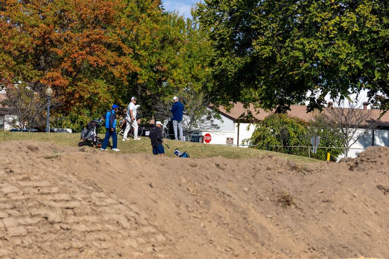 WASHINGTON, DC - OCTOBER 24: Golfers play hole six as trucks unloads debris and soil from the demolition of the White House's East Wing at East Potomac Golf Course on October 24, 2025 in Washington, DC. The demolition is part of U.S. President Donald Trump's plan to build a multimillion-dollar ballroom on the eastern side of the White House. (Photo by Tasos Katopodis/Getty Images)