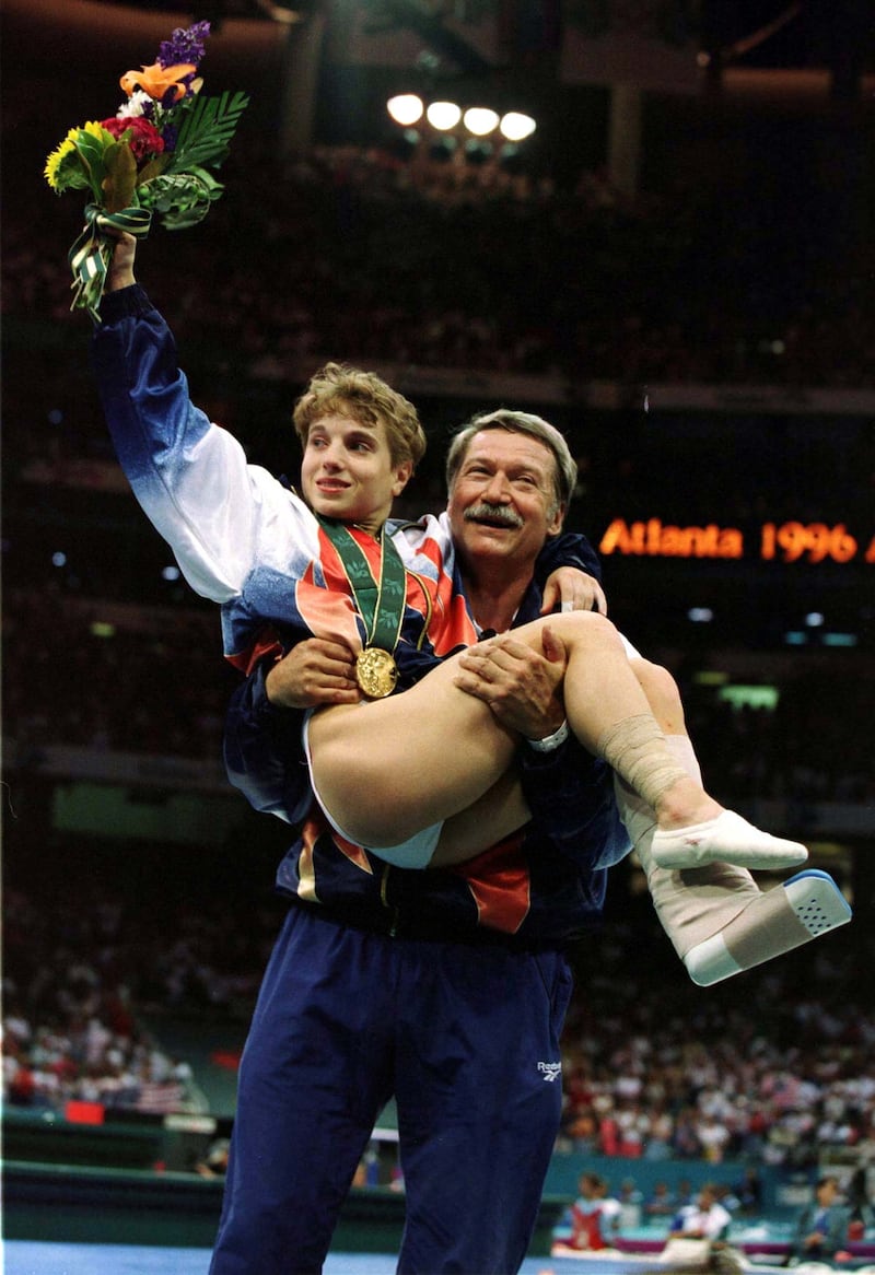 Unofficial United States woman's gymnatics team coach Bela Karolyi lifts Kerry Strug in his arms after the US. won their first Olympic team Gold medal ever with a spectacular optionals performance July 23. Strug injured her left ankle during the vault competition.