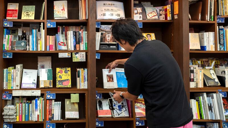This photo taken on August 1, 2024 shows Rokurou Yui, president of book review site All Reviews and president of three shelf-sharing bookstores, working at his bookstore in Tokyo's Kanda Jimbocho district, one of the world's largest "booktowns". There is a growing kind of bookshop in Japan where anyone wanting to sell their tomes can rent a shelf. The concept brings back the joy of browsing real books to communities where many bookstores have shut, and gives readers more eclectic choices than those suggested by algorithms on online sellers, its proponents say. (Photo by Kazuhiro NOGI / AFP) / TO GO WITH Japan-lifestyle-books,FOCUS by Kyoko HASEGAWA
