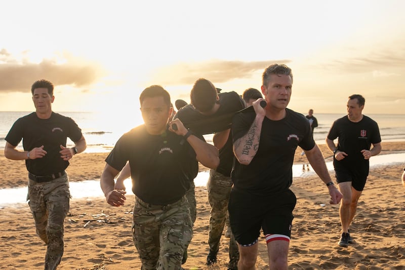 Pete Hegseth helps carrying a soldier on a stretcher while running on a beach as part of a training exercise.