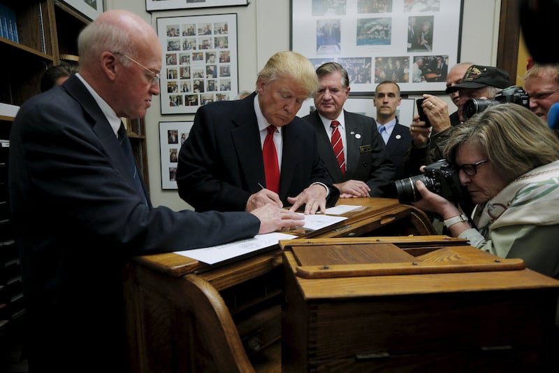 New Hampshire Secretary of State William Gardner (L) watches as U.S. Republican presidential candidate Trump signs his declaration of candidacy to appear on the New Hampshire primary ballot in Concord, New Hampshire, November 4, 2015.  REUTERS/Brian Snyder