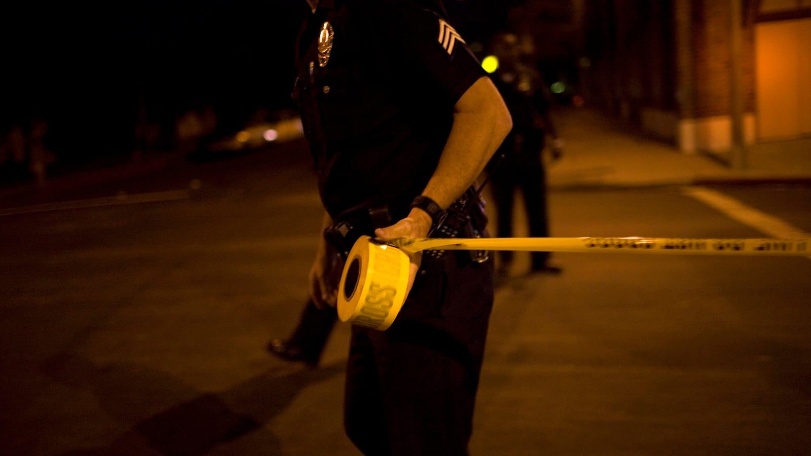 A police officer pulling crime scene tape.
