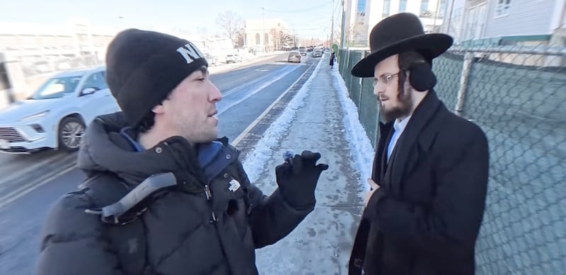 Tyler Oliveira speaks to an Orthodox Jewish man.