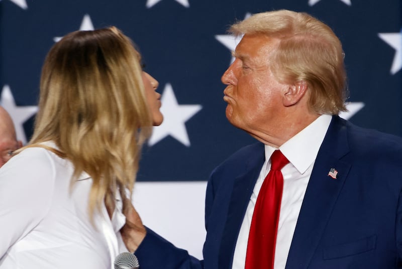 Donald Trump leans in to exchange a kiss with Lara Trump at the end of a town hall as he campaigns in Fayetteville, North Carolina, U.S. October 4, 2024.