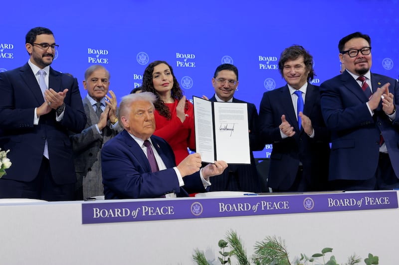 President Donald Trump holds up his signature on the founding charter as Shaikh Isa bin Salman bin Hamad Al Khalifa, Bahrain's Minister of the Prime Minister's Court (L), Prime Minister of Pakistan Shehbaz Sharif (2nd L), President of Kosovo Vjosa Osmani (4th L), Morocco's Foreign Minister Nasser Bourita (3rd R), President of Argentina Javier Milei (2nd R) and Prime Minister of Mongolia Gombojavyn Zandanshatar (R) look on during a signing ceremony for the “Board of Peace” at the World Economic Forum (WEF) on January 22, 2026 in Davos, Switzerland.