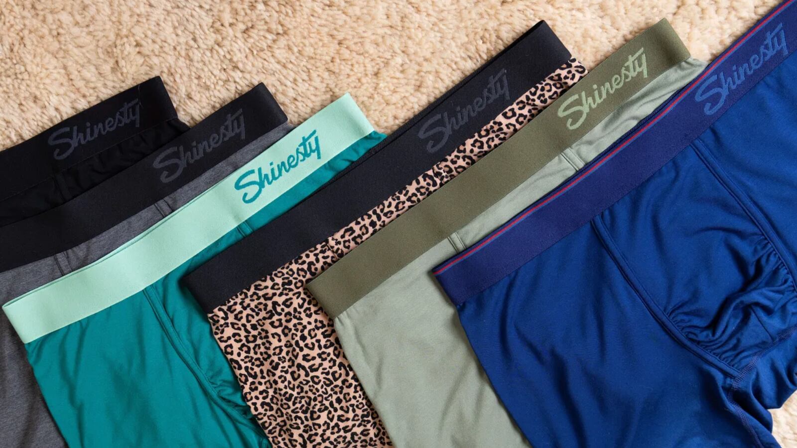 Six pairs on Shinesty underwear on a carpet. They are all different colors and have different designs.