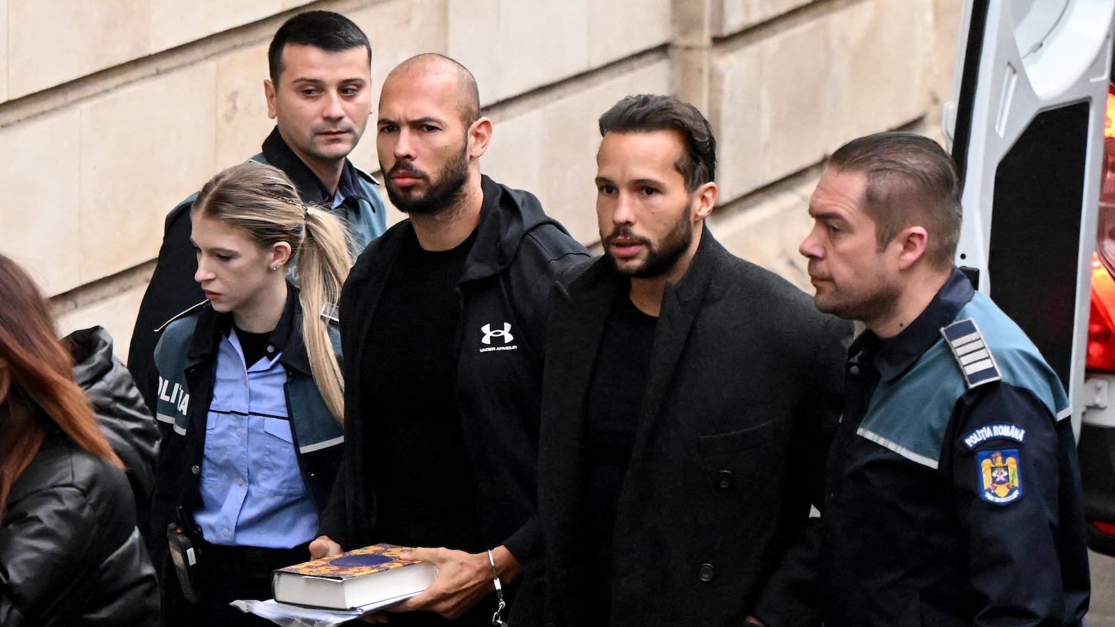 Andrew Tate (3rd R) and his brother Tristan Tate (2nd R) arrive handcuffed and escorted by police at a courthouse in Bucharest on Jan. 10, 2023, for a court hearing.