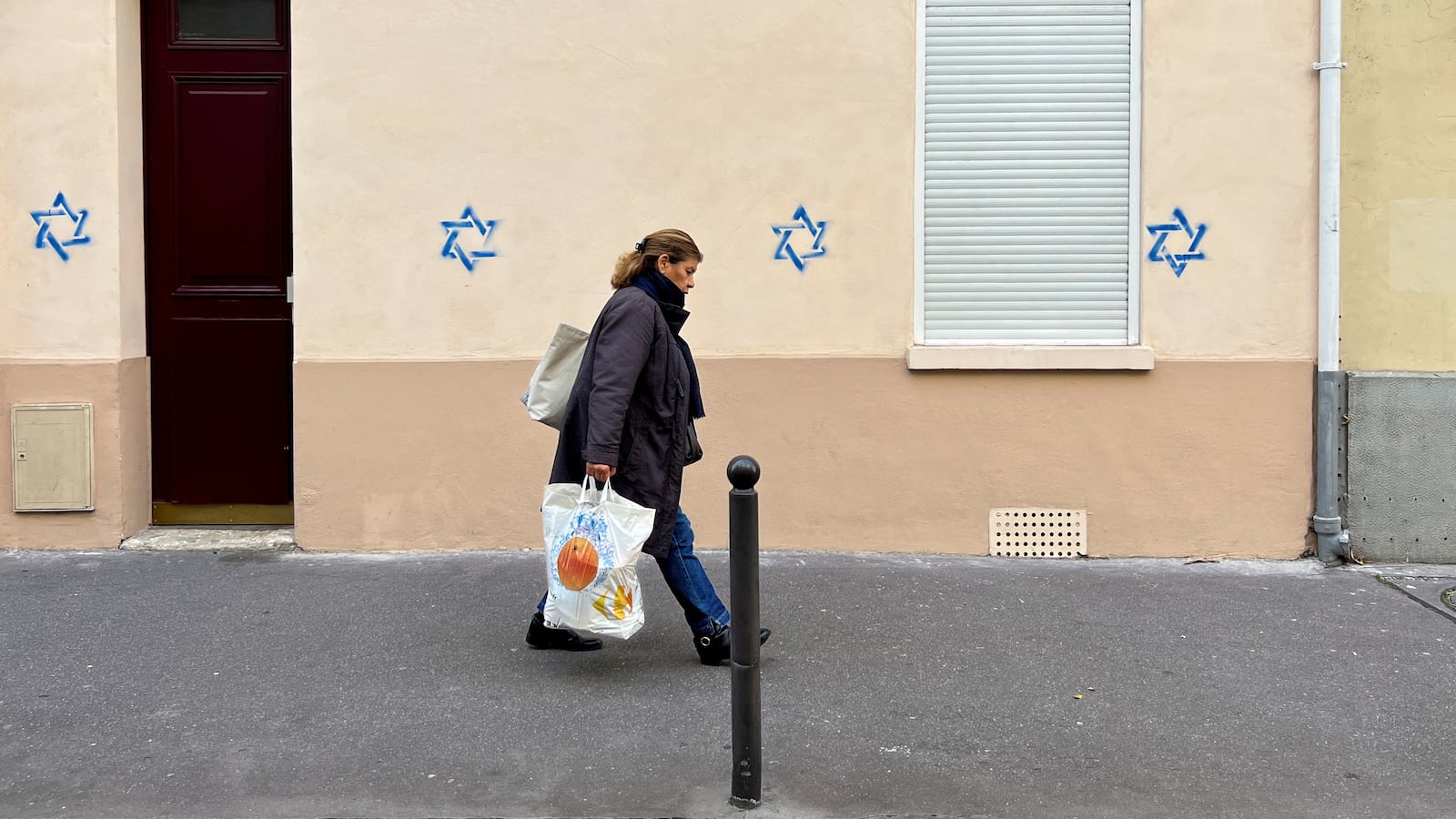 A woman walks past a building tagged with Stars of David in Paris, France, October 31, 2023.
