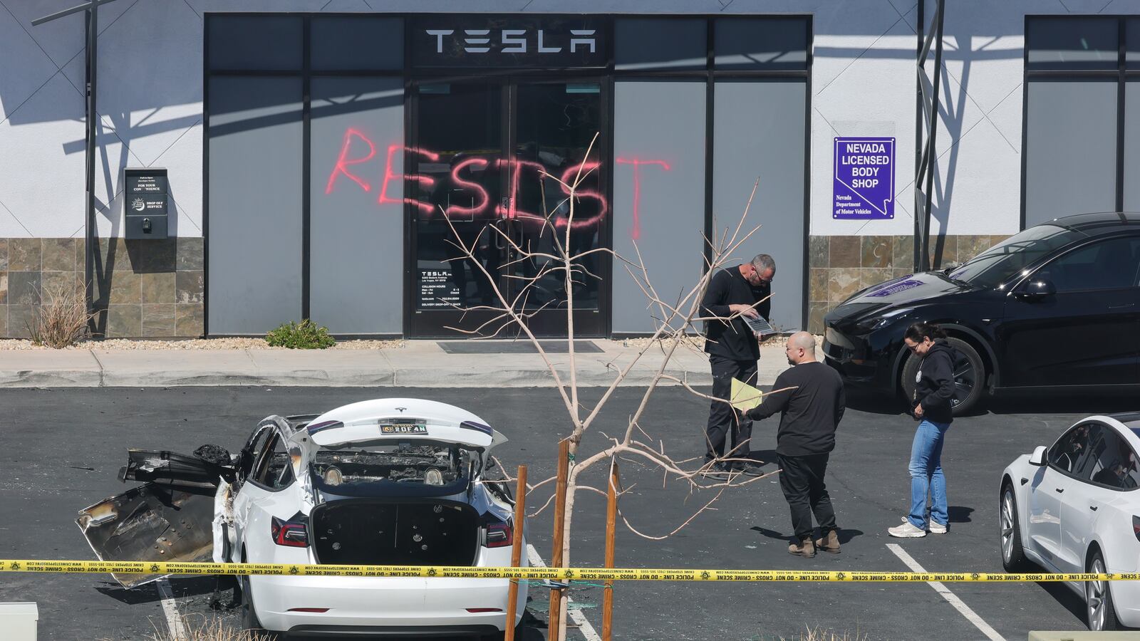 LAS VEGAS, NEVADA - MARCH 18: Investigators look over the scene at a Tesla Collision Center after an individual used incendiary devices to set several vehicles on fire on March 18, 2025 in Las Vegas, Nevada.