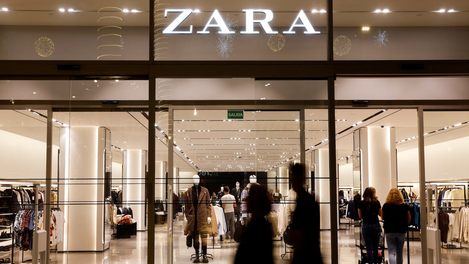 Shoppers walk past a Zara clothes store, part of the Spanish group Inditex, in Las Palmas de Gran Canaria, Spain