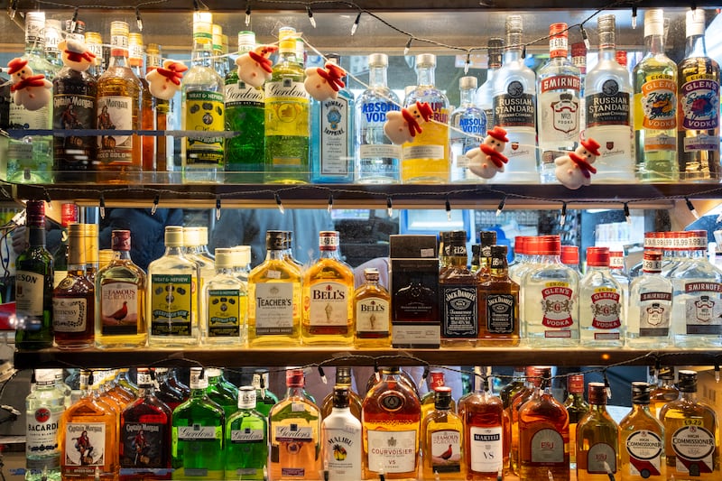 Liquor bottles lined up a store shelf.