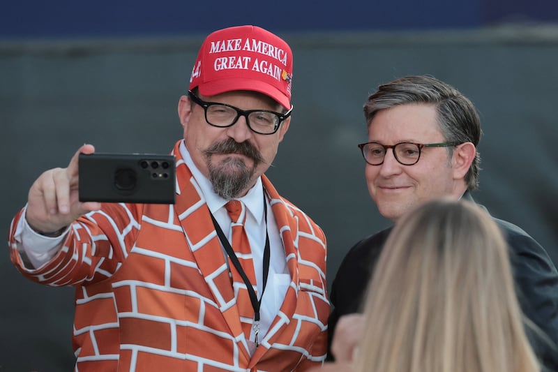 U.S. House Speaker Mike Johnson (R-LA) takes a selfie with a man wearing a suit coat of a brick wall at a rally kicking off the Great American State Fair marking the 250th anniversary of U.S. independence on the National Mall in Washington, D.C., U.S., June 24, 2026. REUTERS/Jonathan Ernst
