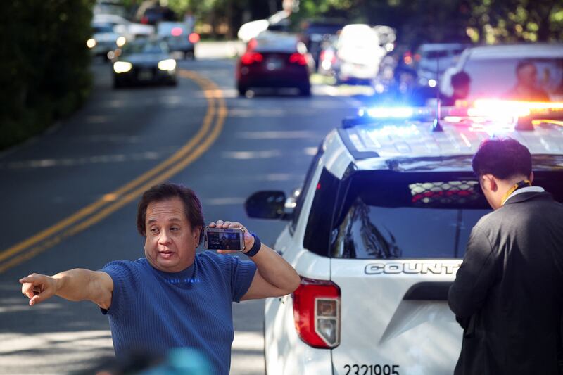 George Conway live streams on his phone outside the home of the former White House national security adviser John Bolton as it is searched by FBI members, in Bethesda, Maryland, Aug. 22, 2025.